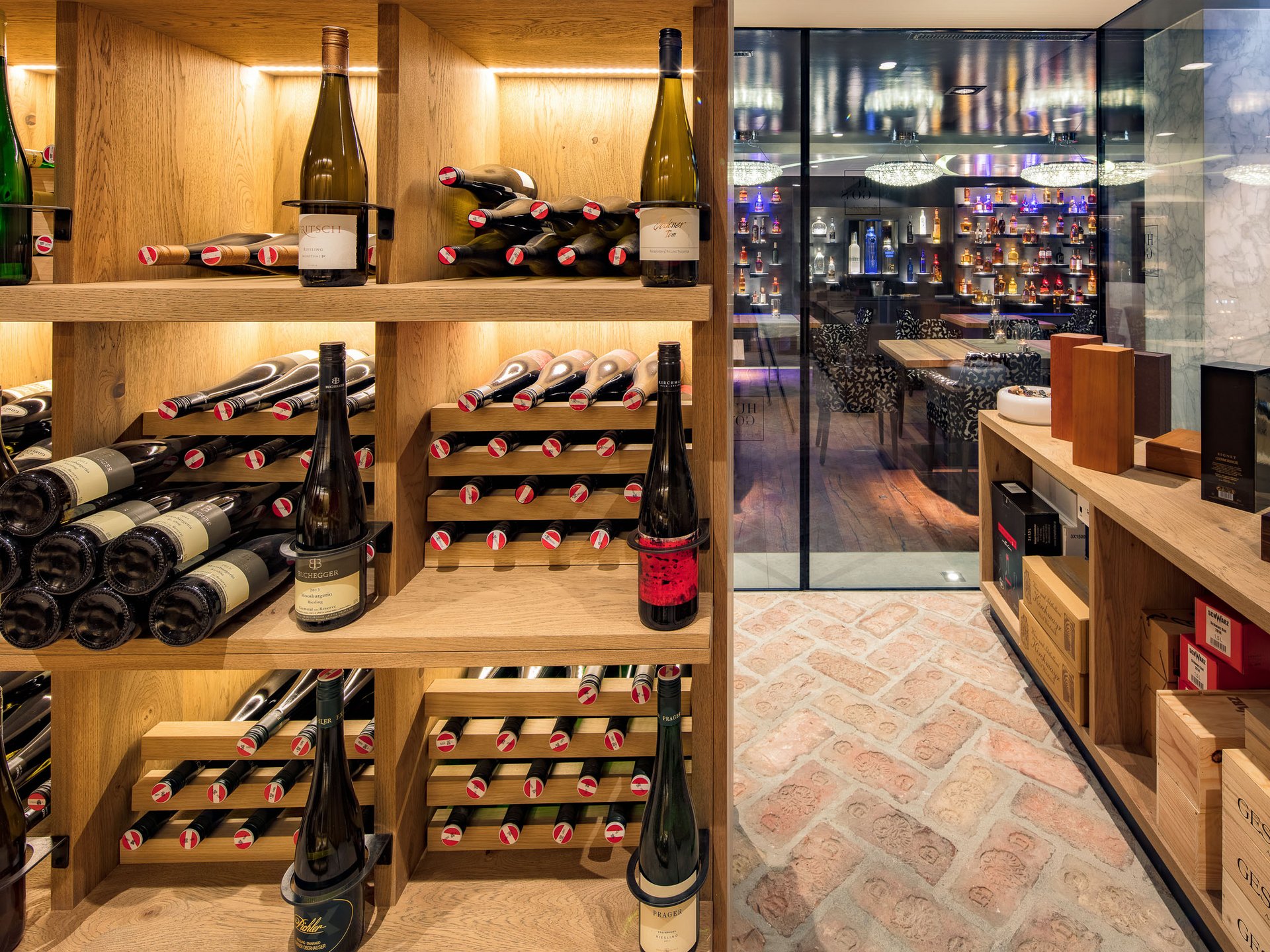 Finest wines and more: wine holiday in Austria at Cervosa Wine cellar with wooden shelves and bar visible through glass in background