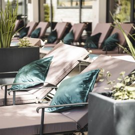 Wohlfühlurlaub im 5-Sterne-Hotel in Serfaus Liegen mit grünen Kissen in einem hellen, modernen Innenbereich mit Pflanzen