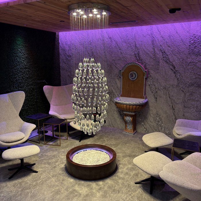 Cervosa – Ihr nachhaltiges Hotel in Österreich Moderner Lounge-Bereich mit Hängelampe, bequemen Sesseln und Steinwand