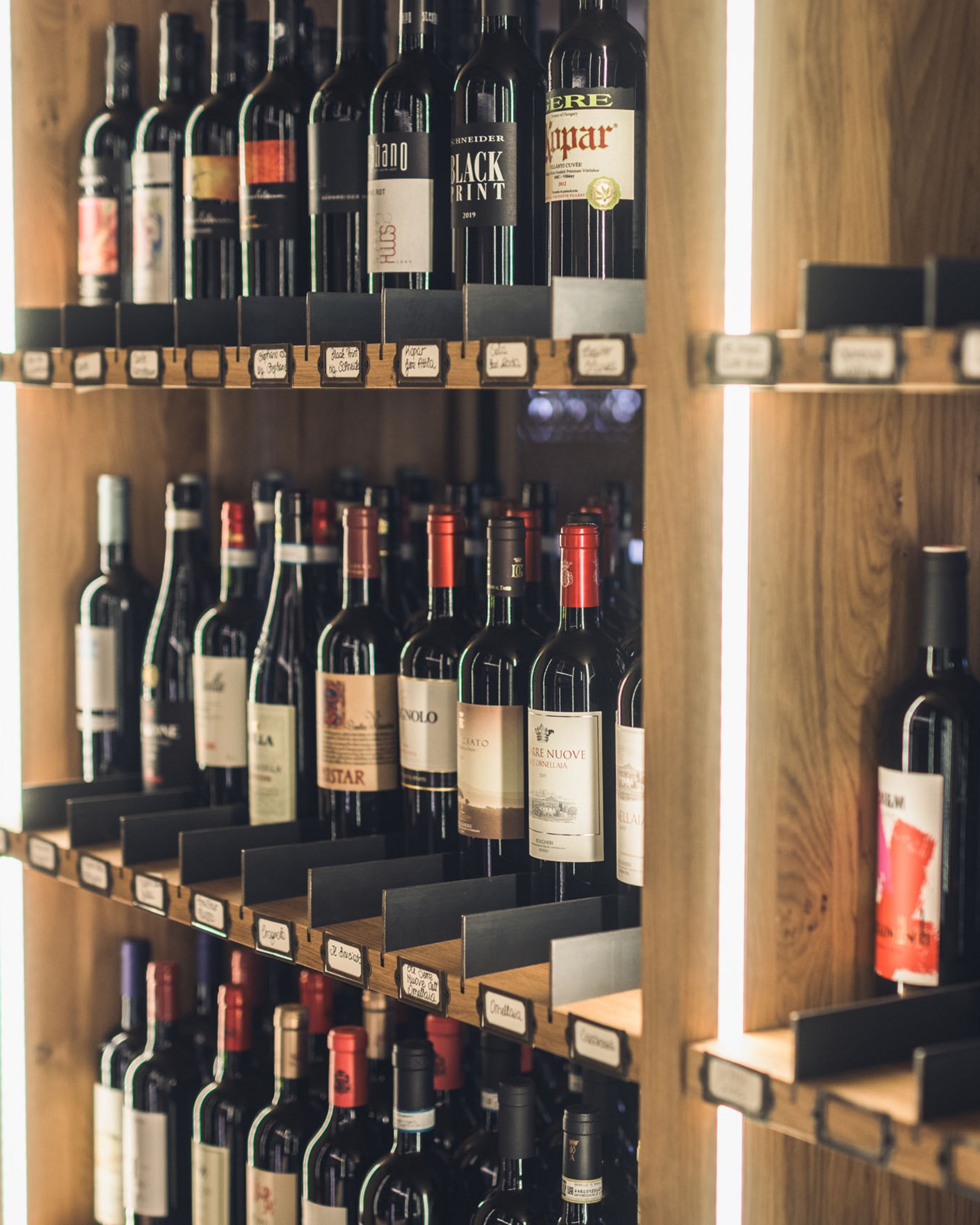 Finest wines and more: wine holiday in Austria at Cervosa Shelves filled with various wine bottles in a wooden rack with lighting