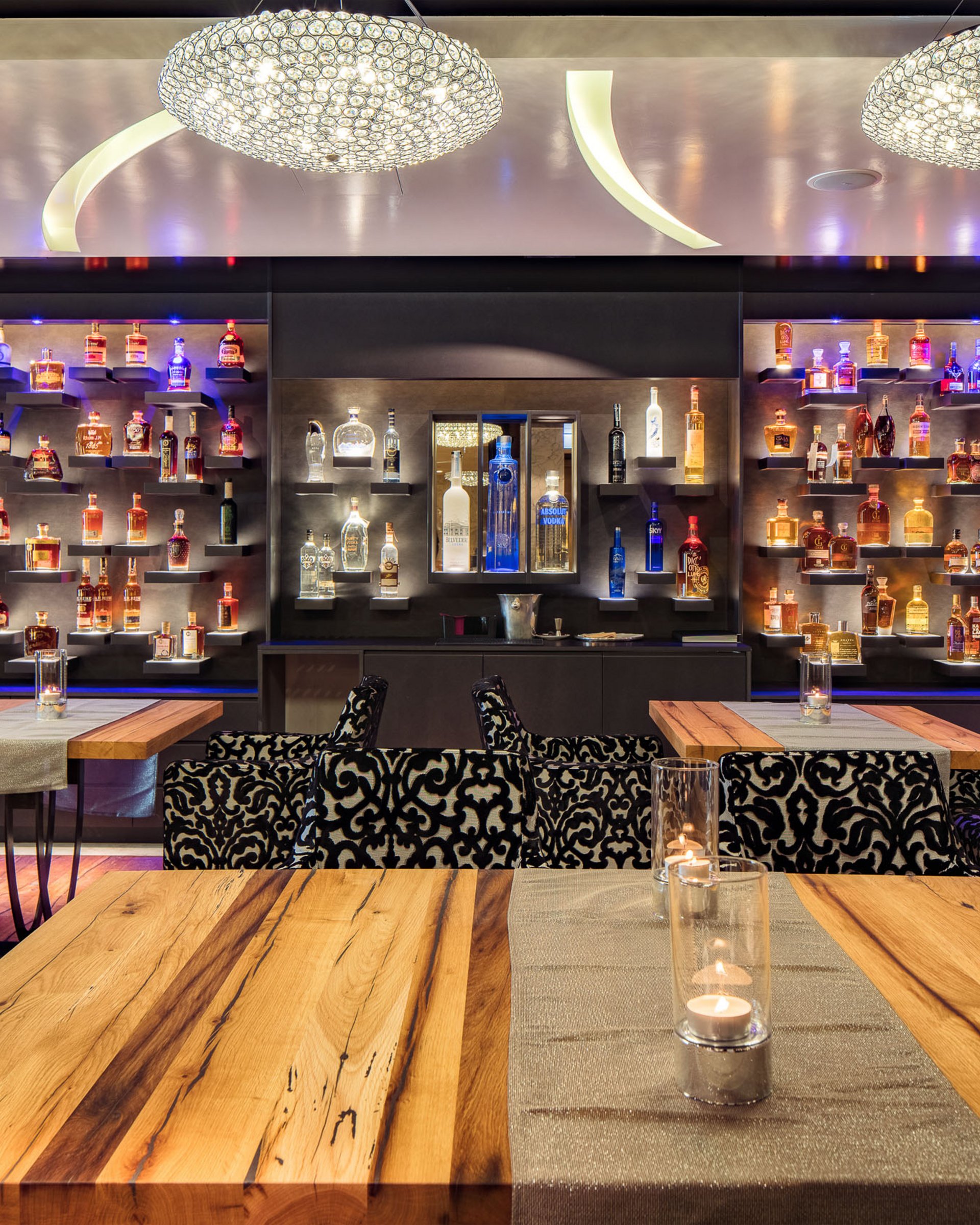 Wohlfühlurlaub im 5-Sterne-Hotel in Serfaus Moderne Bar mit beleuchteten Regalen voll Spirituosen und verzierten Sesseln