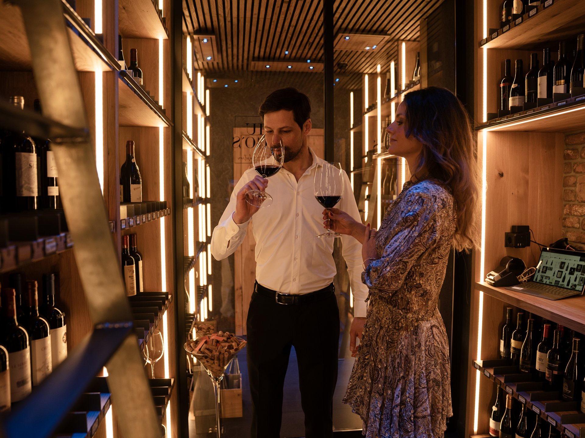 Finest wines and more: wine holiday in Austria at Cervosa Couple tasting wine in a modern wine cellar with wooden shelves and warm lighting