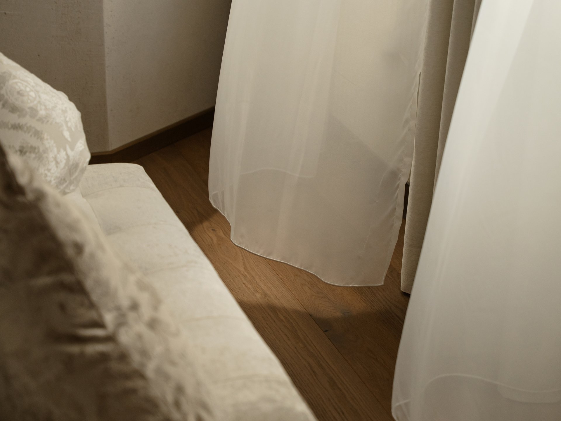 Wohlfühlurlaub im 5-Sterne-Hotel in Serfaus Helles Sofa mit Kissen neben einem Fenster mit weißen Vorhängen