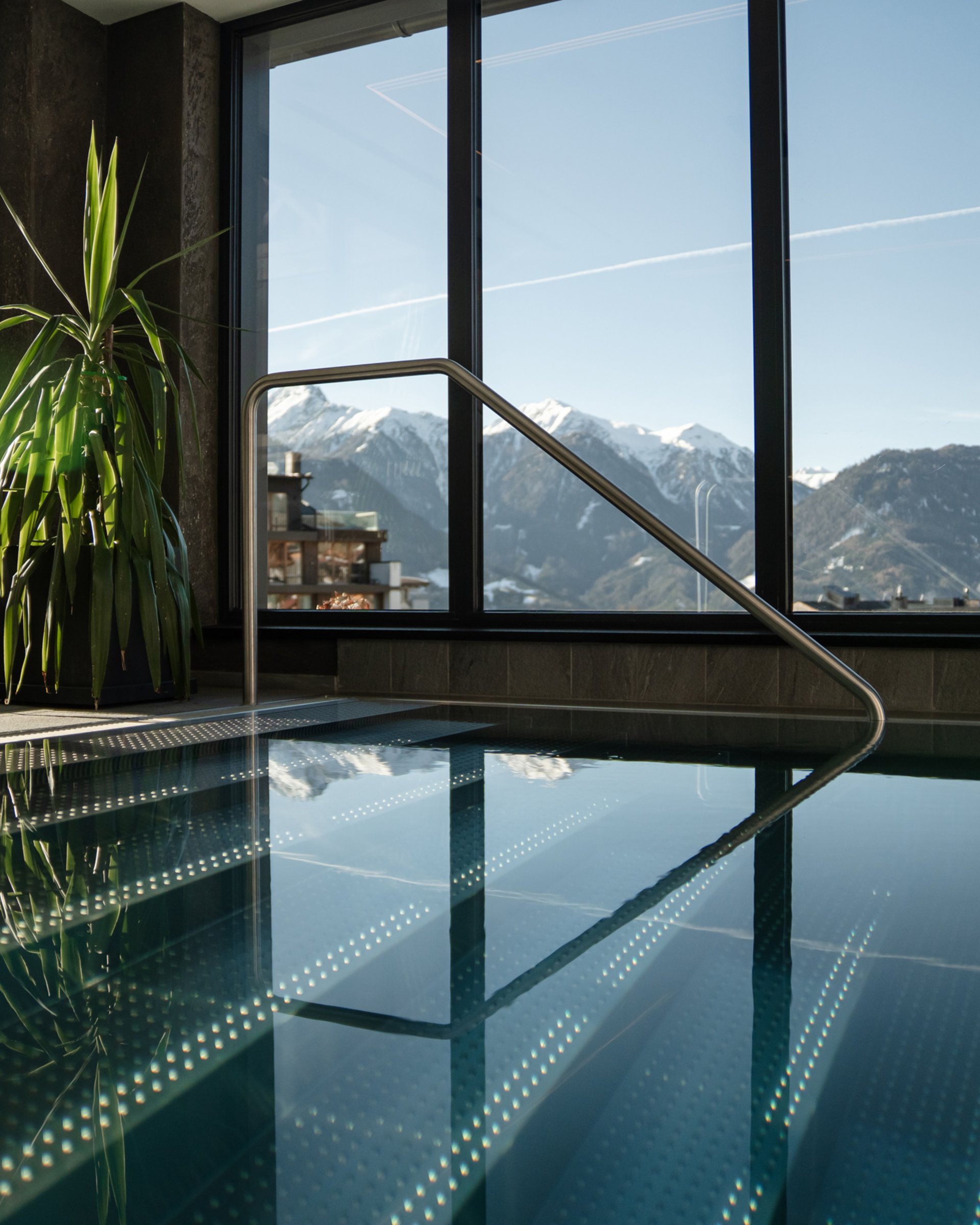 Wohlfühlurlaub im 5-Sterne-Hotel in Serfaus Innenpool mit Panoramafenstern und Blick auf schneebedeckte Berge