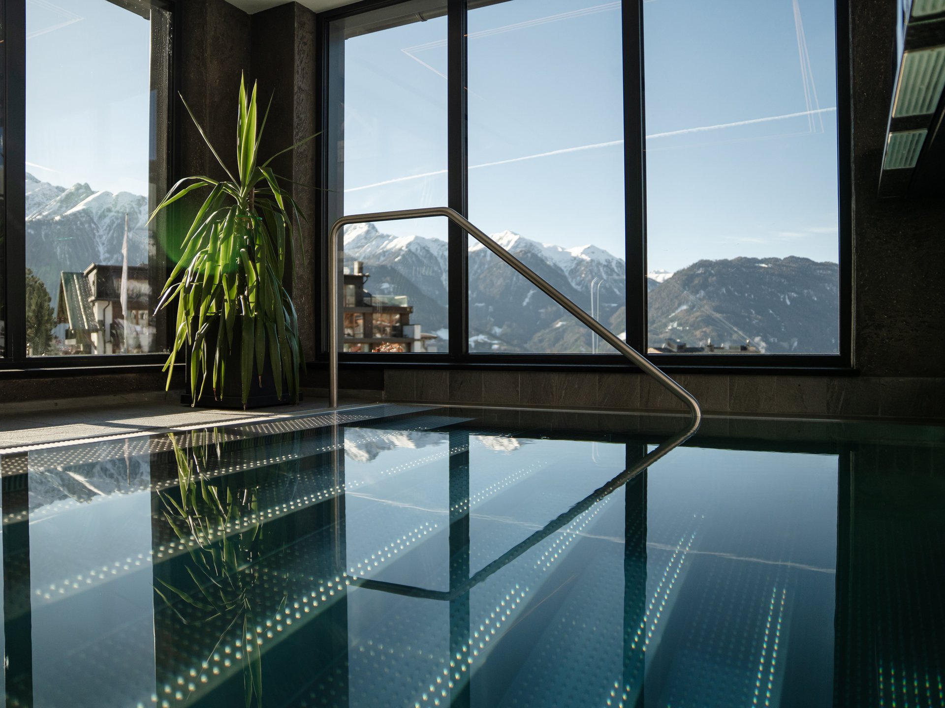 Wohlfühlurlaub im 5-Sterne-Hotel in Serfaus Innenpool mit Panoramafenstern und Blick auf schneebedeckte Berge