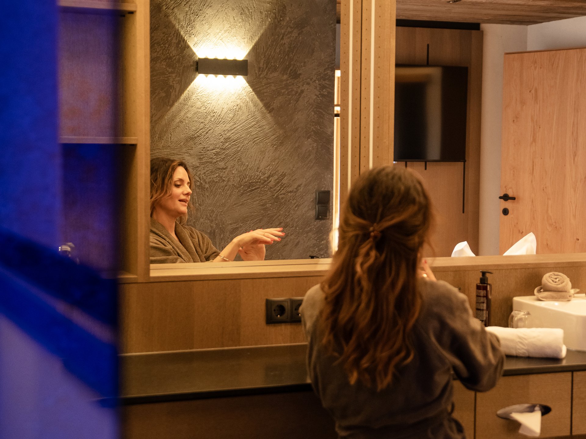 Stay close to nature at Cervosa Woman in bathrobe sitting in front of mirror in modern bathroom.
