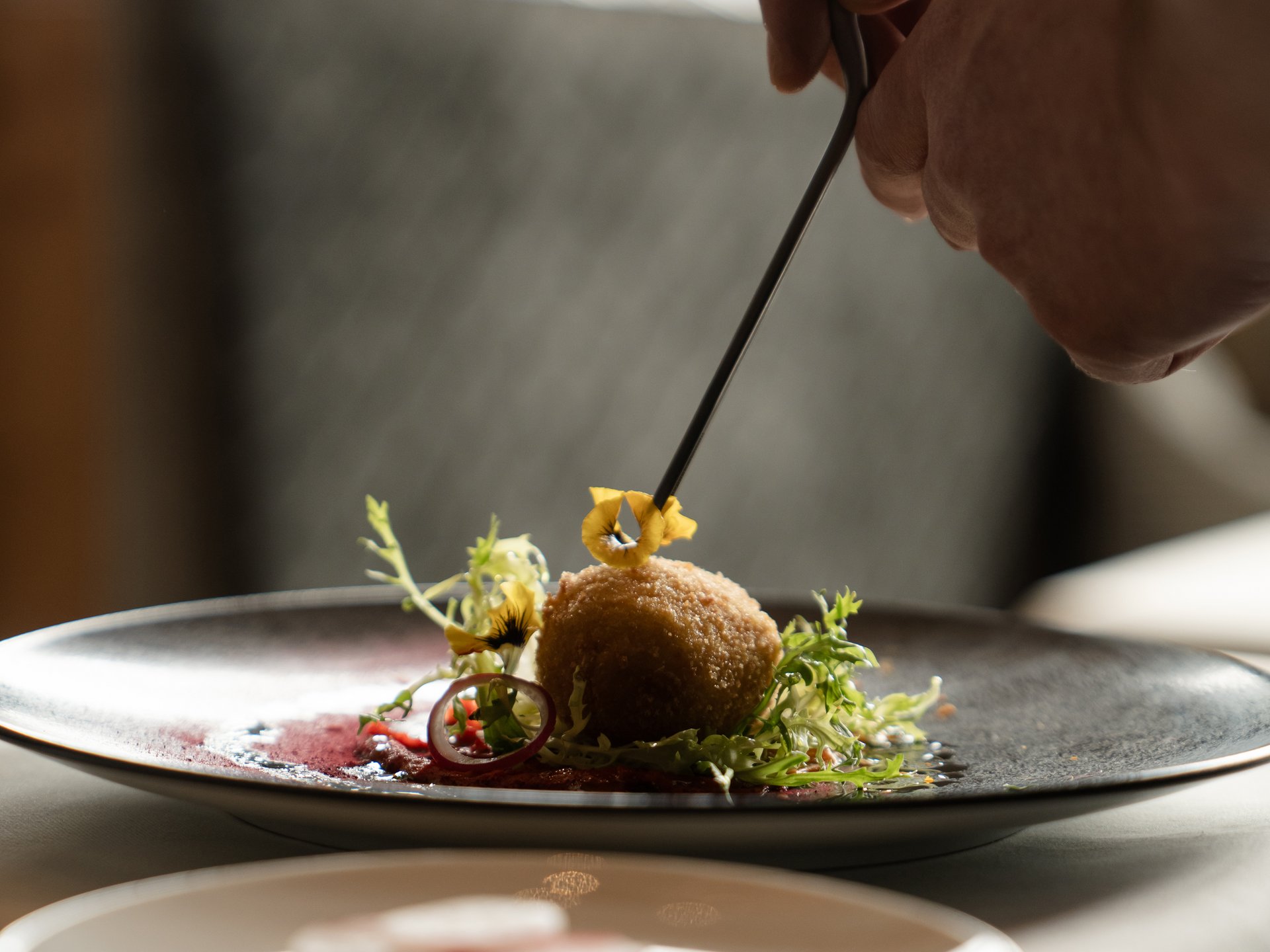 Wohlfühlurlaub im 5-Sterne-Hotel in Serfaus Hand dekoriert Gourmetgericht mit Zange auf Teller in Restaurant