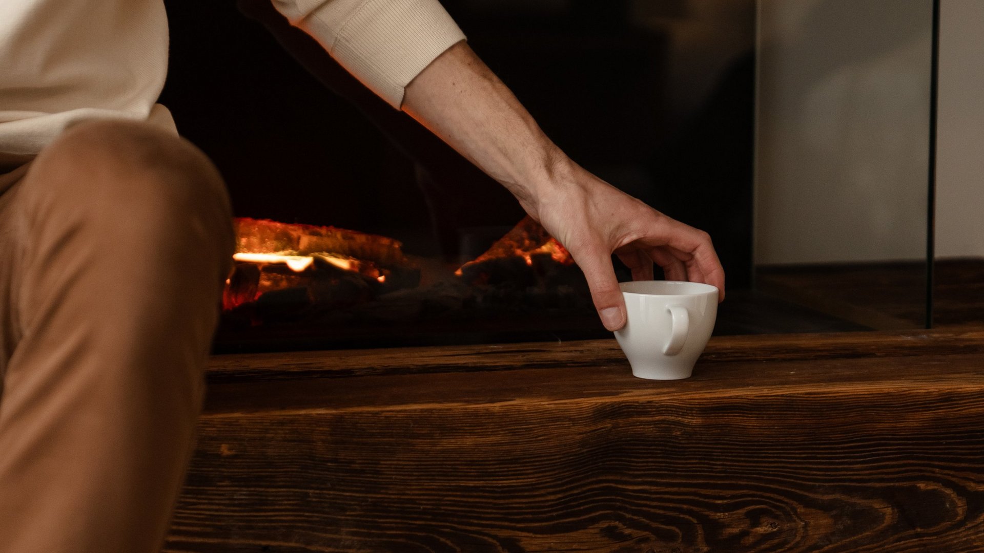 Wohlfühlurlaub im 5-Sterne-Hotel in Serfaus Person greift nach Tasse vor einem modernen elektrischen Kamin