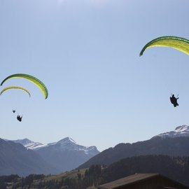 Wohlfühlurlaub im 5-Sterne-Hotel in Serfaus Drei Gleitschirmflieger über Bergen mit blauem Himmel