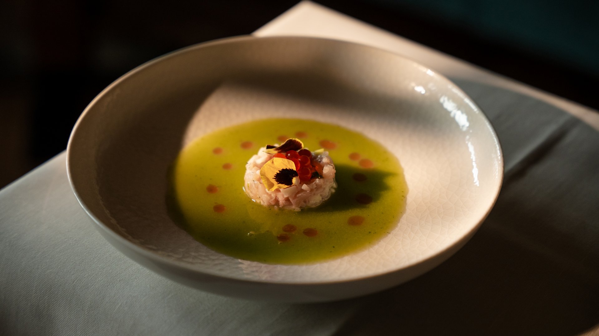 Wohlfühlurlaub im 5-Sterne-Hotel in Serfaus Fein angerichtete Vorspeise mit grüner Sauce und essbaren Blüten in weißer Schale