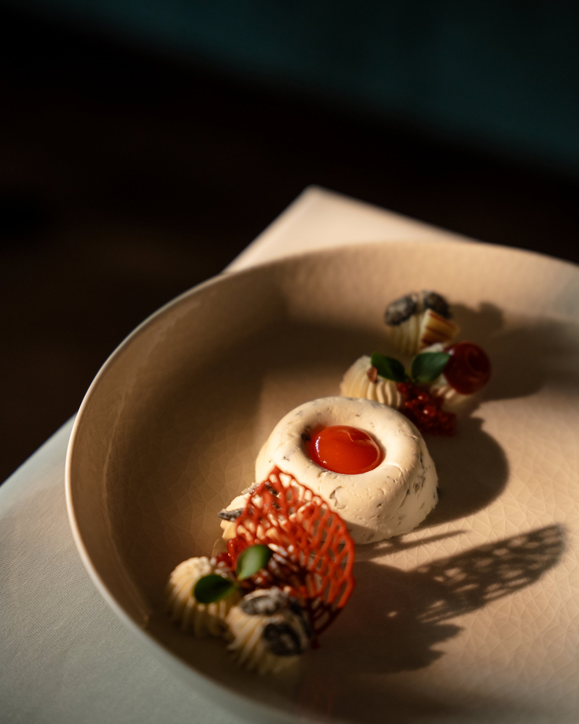 Wohlfühlurlaub im 5-Sterne-Hotel in Serfaus Kunstvoll angerichtetes Dessert mit roter Soße und Dekoration auf beigem Teller