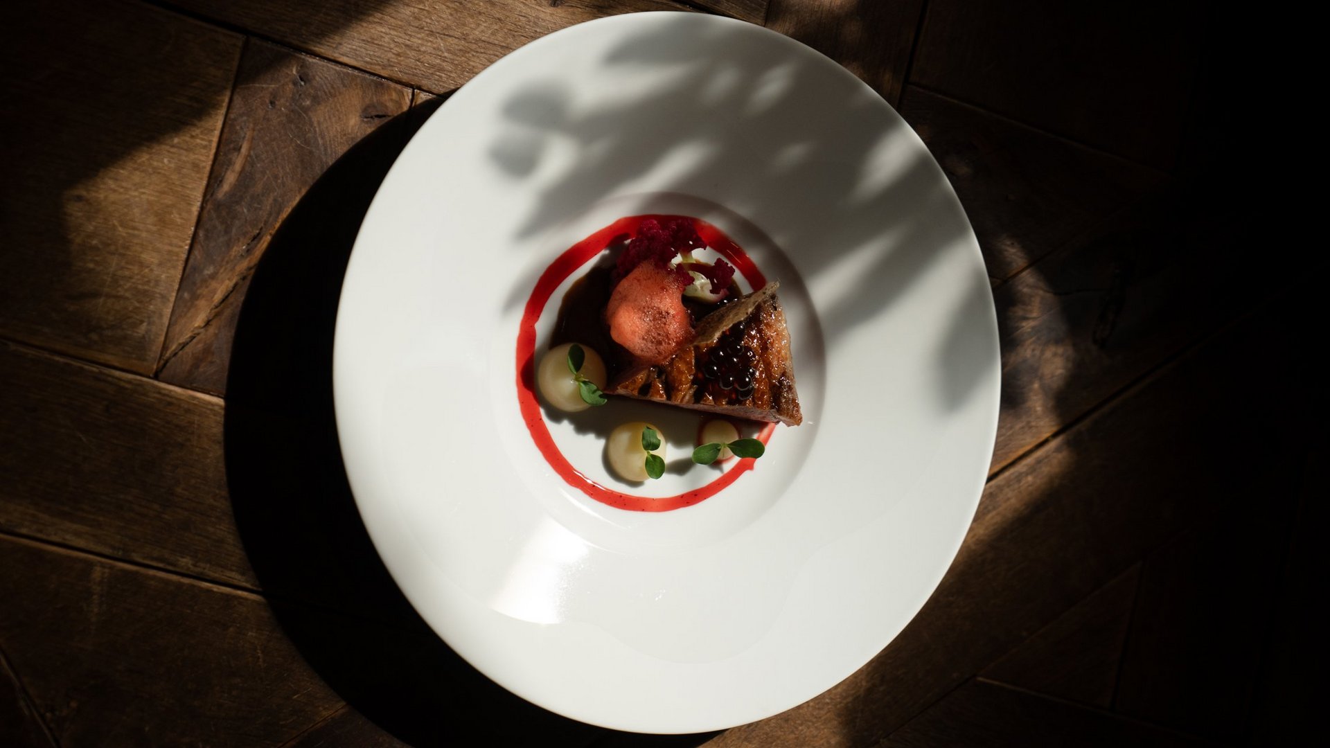 Wohlfühlurlaub im 5-Sterne-Hotel in Serfaus Fein angerichtetes Gourmetgericht auf weißem Teller mit dunklem Holzboden